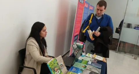Mujer sentada junto con libros y un hombre leyendo