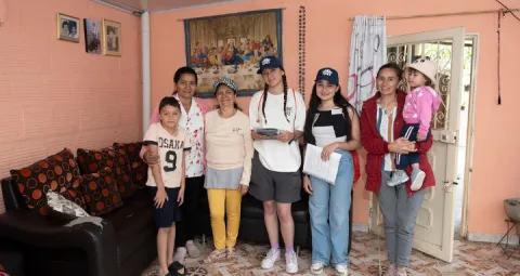 Estudiantes visitan y conversan con una familia en su hogar, generando vínculos cercanos.