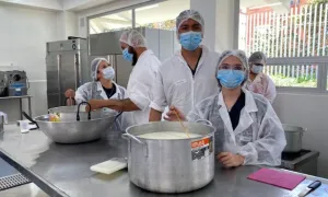 Participantes del curso de lácteos con una olla de leche