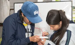 Dos jóvenes colaboran concentradamente en el armado de un dispositivo.