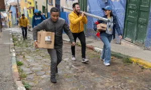 Estudiantes lasallistas suben una calle empedrada cargando materiales para una jornada