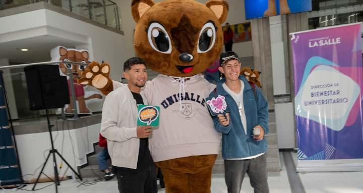 Dos jóvenes junto a la mascota de la universidad Juana