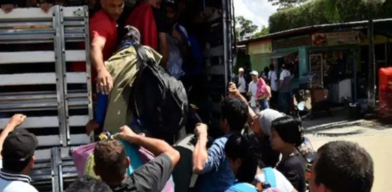 Un grupo de personas está subiendo a un camión y varias personas cargando...