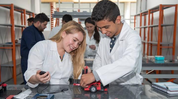 2 Jóvenes con bata blanca en un laboratorio realizando un proyecto